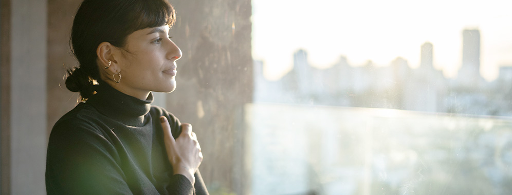 Eine Frau mit entspanntem Gesichtsausdruck schaut aus dem Fenster.